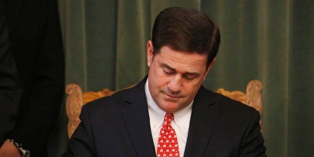 Arizona Republican Gov. Doug Ducey signs the American Civics Act into law during a bill signing ceremony at the Capitol, Tuesday, Feb. 24, 2015, in Phoenix. (AP Photo/Ross D. Franklin)