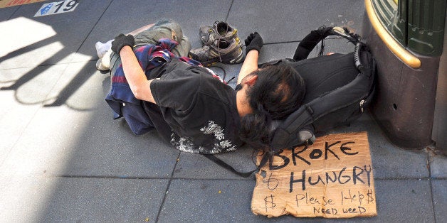 SAN FRANCISCO, CA - OCTOBER 4, 2013: A homeless man sleeps on a sidewalk in San Francisco's Union Square district. His sign declares that he is 'broke and hungry' and 'needs weed.' (Photo by Robert Alexander/Getty Images)