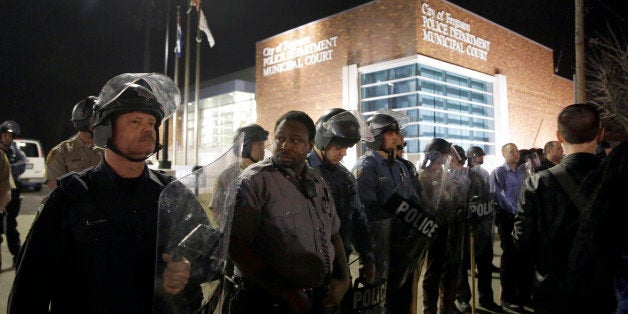 Police form a line outside the Ferguson Police Department as people demonstrate nearby Wednesday, March 11, 2015, in Ferguson, Mo. Earlier in the day, the resignation of Ferguson police chief Thomas Jackson was announced in the wake of a scathing Justice Department report prompted by the fatal shooting of an unarmed black 18-year-old by a white police officer. (AP Photo/Jeff Roberson)