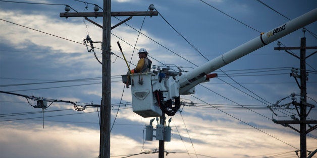 Workers with T&D Solutions work to repair power lines along Highway 58 in Emerald Isle, N.C., Friday, July 4, 2014. Hurricane Arthur began moving offshore and away from North Carolina's Outer Banks early Friday after hitting the state's barrier islands overnight and causing flooding and thousands of power outages. (AP Photo/Randall Hill)