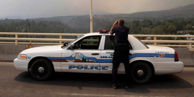 Los Alamos police officer Doug Ehler peers through binoculars to look at smoke from the Las Conchas fire in Los Alamos, N.M., Tuesday, June 28, 2011. A vicious wildfire spread through the mountains above a northern New Mexico town on Tuesday, driving thousands of people from their homes as officials at the government nuclear laboratory tried to dispel concerns about the safety of sensitive materials. (AP Photo/Jae C. Hong)