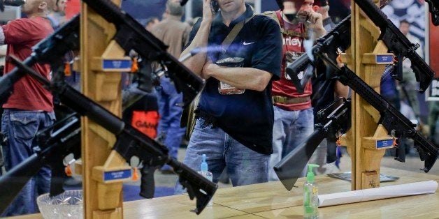 A trade show attendee browses the Rock River Arms assault rifle display at the Shooting Hunting and Outdoor Trade Show, Tuesday, Jan. 14, 2014, in Las Vegas. (AP Photo/Julie Jacobson)