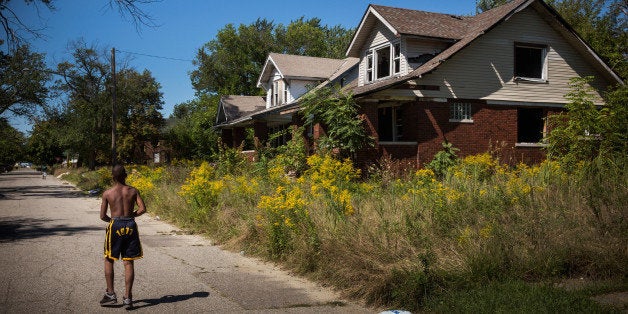 DETROIT, MI - SEPTEMBER 04: Lawrence Payne walks past two abandoned houses on September 4, 2013 in the Six Mile Gratiot neig