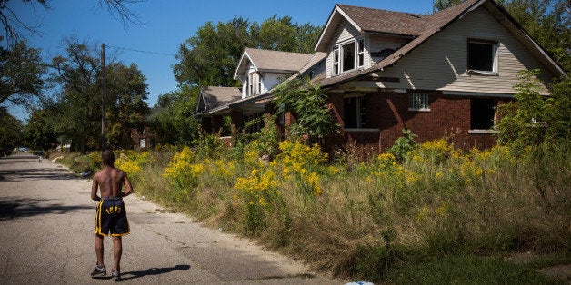 DETROIT, MI - SEPTEMBER 04: Lawrence Payne walks past two abandoned houses on September 4, 2013 in the Six Mile Gratiot neighborhood of Detroit, Michigan. Detroit has an estimated 78,000 abandoned buildings across its 142 square miles. Last month the city declared bankruptcy, the largest municipality to ever do so in the United States. (Photo by Andrew Burton/Getty Images)