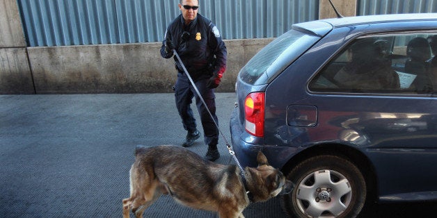 NOGALES, AZ - DECEMBER 10: U.S. border officer Michael Avelar and drug-sniffing German Shepherd Ali inspect a vehicle enteri