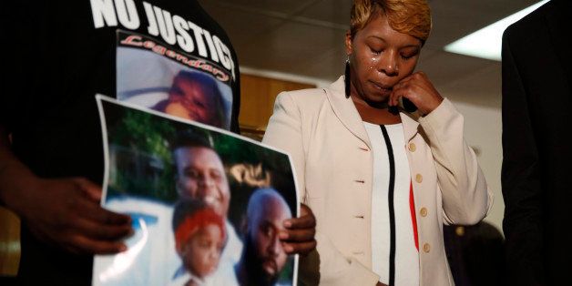 FILE - In this Aug. 11, 2014 file photo, Lesley McSpadden, the mother of 18-year-old Michael Brown, wipes away tears as Brown's father, Michael Brown Sr., holds up a family picture of himself, his son, top left, and a young child during a news conference in Jennings, Mo. Lingering questions about Michael Brown could be answered Wednesday as two news organizations seek the release of any possible juvenile records for the unarmed 18-year-old who was shot by a police officer last month.(AP Photo/Jeff Roberson, File)