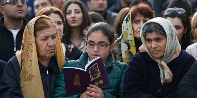 Armenians attend service in Echmiadzin, the religious center of the Armenian Church outside the Armenian capital, Yerevan, Thursday, April 23, 2015. The Armenian Apostolic Church, the country's dominant religion, held services Thursday to canonize all victims. On Friday, April 24, Armenians will mark the centenary of what historians estimate to be the slaughter of up to 1.5 million Armenians by Ottoman Turks, an event widely viewed by scholars as genocide. Turkey, however, denies the deaths constituted genocide and says the death toll has been inflated. (AP Photo/Sergei Grits)