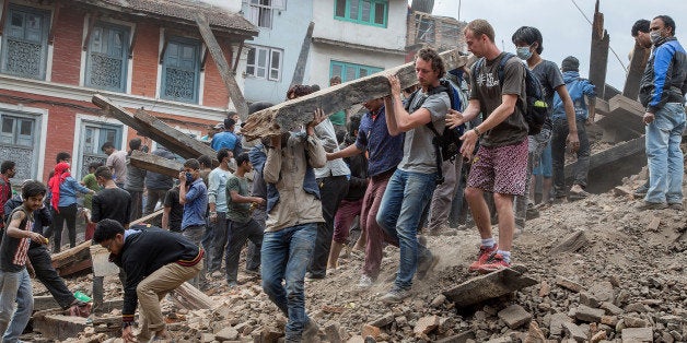 KATHMANDU, NEPAL - APRIL 25: Emergency workers and bystanders clear debris while searching for survivors under a collapsed te
