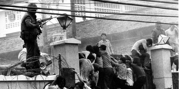 Mobs of Vietnamese people scale the wall of the U.S. Embassy in Saigon, Vietnam, trying to get to the helicopter pickup zone, just before the end of the Vietnam War on April 29, 1975. (AP Photo/Neal Ulevich)