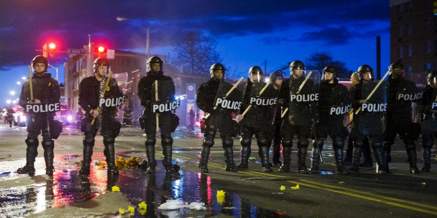 Police stand guard Monday, April 27, 2015, after rioters plunged part of Baltimore into chaos, torching a pharmacy, setting police cars ablaze and throwing bricks at officers. (AP Photo/Matt Rourke)