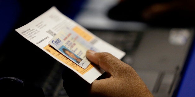 FILE - In this Feb. 26, 2014 file photo, an election official checks a voter's photo identification at an early voting polling site in Austin, Texas. A majority of the nation's highest court on Saturday Oct. 18, 2014 rejected an emergency request from the Justice Department and civil rights groups to prohibit the state from requiring voters to produce certain forms of photo identification in order to cast ballots. (AP Photo/Eric Gay, File)