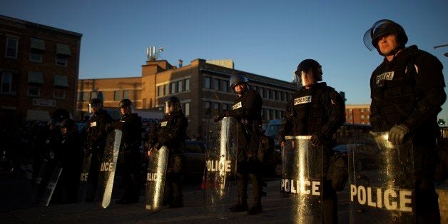 BALTIMORE, MD - APRIL 28: Riot police are illuminated by late afternoon light as they line the street to form a blockade aft