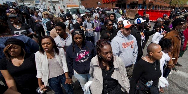 People clasp hand and sing the hymn "Amazing Grace" Tuesday, April 28, 2015, in Baltimore, in the aftermath of rioting following Monday's funeral for Freddie Gray, who died in police custody. The streets were largely calm in the morning and into the afternoon, but authorities remained on edge against the possibility of another outbreak of looting, vandalism and arson. (AP Photo/Matt Rourke)