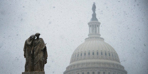 Snow begins to gather on a statue outside the US Capitol Building in Washington, DC, December 10, 2013. Fresh winter snow moved into the US mid-Atlantic region on Tuesday, shutting schools and offices in the nation's capital and elsewhere as the mid-section of the US remained in the grip of Arctic air that showed no signs of easing. AFP PHOTO / Jim WATSON (Photo credit should read JIM WATSON/AFP/Getty Images)