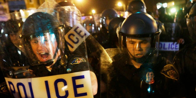 Police in riot gear push back on media and a crowd gathering in the street after a 10 p.m. curfew went into effect Thursday, April 30, 2015, in Baltimore. The curfew was imposed after unrest in the city over the death of Freddie Gray while in police custody. (AP Photo/David Goldman)