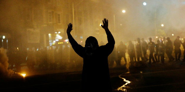 A protestor walks away as police in riot gear advance on the crowd after a 10 p.m. curfew went into effect in the wake of Monday's riots following the funeral for Freddie Gray, Tuesday, April 28, 2015, in Baltimore. (AP Photo/David Goldman)