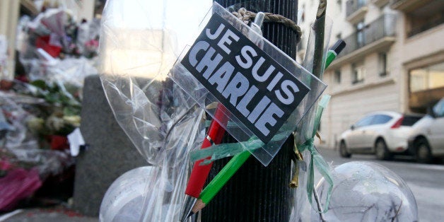Flowers are laid near the headquarters of magazine Charlie Hebdo in Paris, Friday Feb. 6, 2015. Brothers Said and Cherif Koua