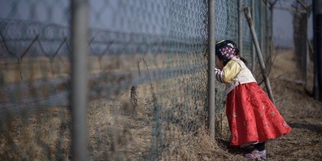 A girl wearing a traditional hanbok dress stands at a military fence facing towards North Korea at Imjingak park, south of the Military Demarcation Line and Demilitarized Zone (DMZ) separating North and South Korea, on February 19, 2015. South Korean families separated during the Korean war often visit the DMZ to offer prayers to their relatives in the North, on the occasion of the Lunar New Year. AFP PHOTO / Ed Jones (Photo credit should read ED JONES/AFP/Getty Images)