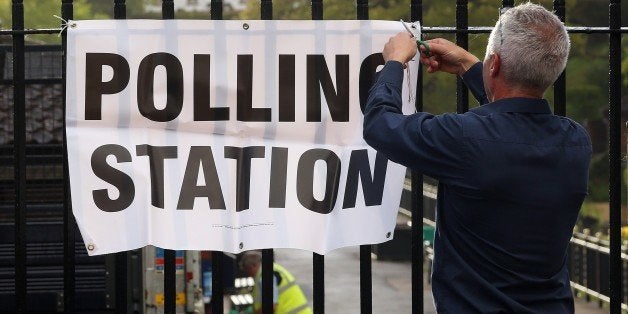 An official attaches a sign to a fence outside a polling station set up at the Cafe on the Promenade at Roath Park in Cardiff, south Wales on May 7, 2015, as Britain holds a general election. Polls opened Thursday in Britain's closest general election for decades with voters set to decide between the Conservatives of Prime Minister David Cameron, Ed Miliband's Labour and a host of smaller parties. (Photo credit should read GEOFF CADDICK/AFP/Getty Images)