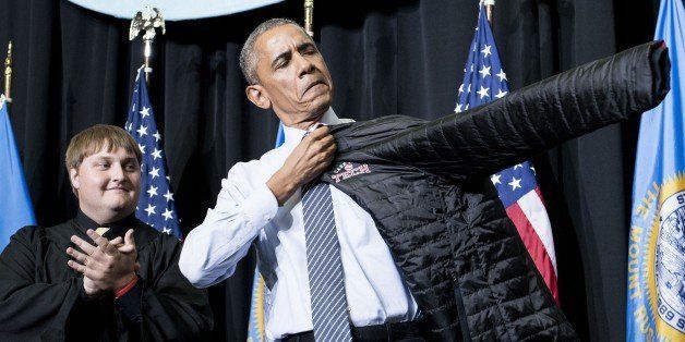 US President Barack Obama puts on at a jacket given to him after speaking during a commencement ceremony at Lake Area Technical Institute in Watertown, South Dakota on May 8, 2015. South Dakota is the last of the 50 states Obama has visited as President. AFP PHOTO/BRENDAN SMIALOWSKI (Photo credit should read BRENDAN SMIALOWSKI/AFP/Getty Images)