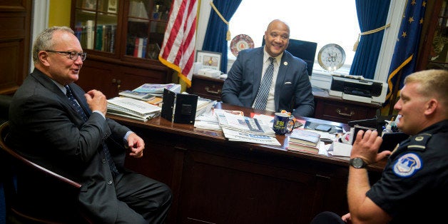 UNITED STATES - MAY 12: Capitol Police officer Nicholas Simons meets with Gary Langston, left, of the Indiana Motor Truck Association, in Rep. Andre Carson's, D-Ind., center, Rayburn Building office, May 12, 2015. Simons preformed CPR on Langston last year on the Hill and is credited with saving his life after he stopped breathing. (Photo By Tom Williams/CQ Roll Call)