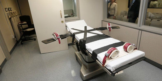 In this Oct. 9, 2014 file photo, Department of Corrections officials are pictured in the witness room at right, outside the newly renovated death chamber at the Oklahoma State Penitentiary in McAlester, Okla. With executions in Oklahoma on hold amid a constitutional review of its lethal injection formula, Republican legislators are pushing to make Oklahoma the first state in the nation to allow the use of nitrogen gas to execute death row inmates. (AP Photo/Sue Ogrocki, File)