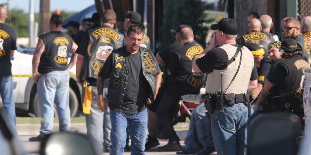 People stand as officers investigate a shooting in the parking lot of the Twin Peaks restaurant Sunday, May 17, 2015, in Waco, Texas. Authorities say that the shootout victims were members of rival biker gangs that had gathered for a meeting. (AP Photo/Jerry Larson)