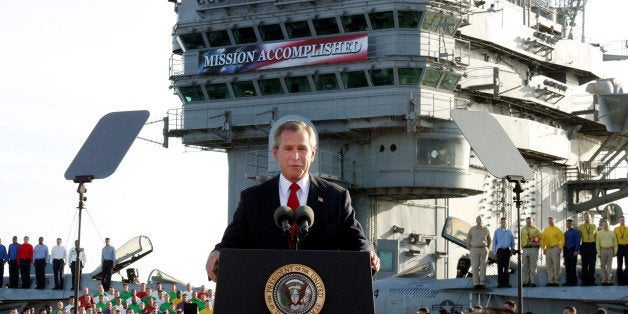 FILE - In this May 1, 2003 file photo, President George W. Bush speaks aboard the aircraft carrier USS Abraham Lincoln off the California coast. As slogans go, President Barack Obama's promise of the âlight of a new dayâ in Afghanistan isn't as catchy as the âMission Accomplishedâ banner that hung across the USS Abraham Lincoln the day President George W. Bush announced the end of major combat operations in Iraq. (AP Photo/J. Scott Applewhite, File)