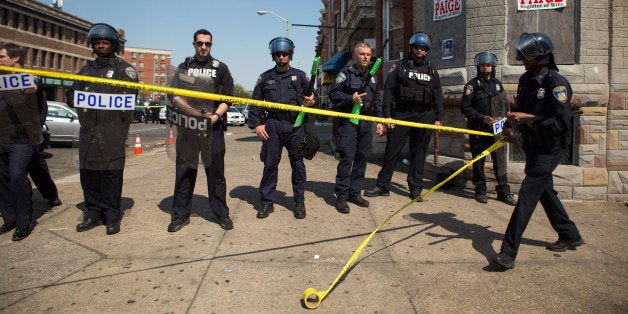 BALTIMORE, MD - MAY 4: An officer rolls out police tape as other officers form a line to block North Ave., near the site of recent riots and only several blocks away from where Freddie Gray was arrested last month, May 4, 2015 in Baltimore, Maryland. Initial reports that a man had been shot by police sparked anger in the crowd. Officials later reported that no one had been injured and the gun, carried by a man seen carrying on a security camera, had discharged accidentally. (Photo by Allison Shelley/Getty Images)