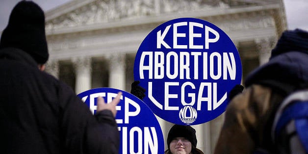 WASHINGTON, UNITED STATES: Pro-choice supporter and intern with the National Organization for Women, Meredith Harper, smiles as she ignores the pleadings of pro-life protesters that abortion is wrong in front of the US Supreme Court during the March for Life demonstration 22 January, 2004, in Washington, DC. US President George W. Bush praised anti-abortion marchers for their 'noble cause' as Democrats in Congress introduced a bill to block US government interference in reproductive rights. The annual march takes place every 22 January, the anniversary of the 1973 Roe vs. Wade Supreme Court decision legalizing abortion. AFP PHOTO / TIM SLOAN (Photo credit should read TIM SLOAN/AFP/Getty Images)