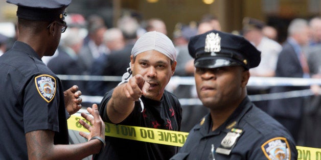 A witness talks with police at a Manhattan crime scene, Wednesday, May 13, 2015, in New York, after a man apparently wielding a hammer was shot and wounded by police. The shooting took place shortly after 10 a.m., blocks from Madison Square Garden and Penn Station. (AP Photo/Mark Lennihan)