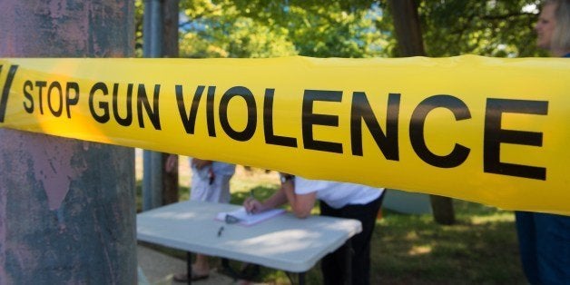 Members of the Coalition of Gun Violence Prevention sign-in behind their version of 'Police Line' perimeter tape, for their monthly protest outside the National Rifle Association(NRA) headquarters August 14, 2014, in Fairfax, Virginia. The group has been protesting monthly on the doorstep of the NRA for a year and half calling for common-sense legislative gun reforms. AFP PHOTO/Paul J. Richards (Photo credit should read PAUL J. RICHARDS/AFP/Getty Images)