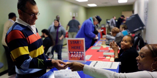 In this Wednesday, Feb. 26, 2014 photo, an election official checks a voter's photo identification at an early voting polling