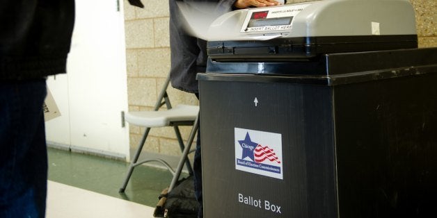 A voter slides his ballot into the ballot box at a polling place on the Northside of Chicago, Illinois on November 6, 2012. C