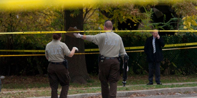 Two members of the St. Louis County Police crime scene investigation unit make their way through a maze of crime scene tape t