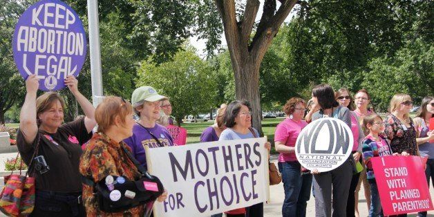 Protesters hold signs during a rally at the Statehouse in Topeka, Kan., Wednesday, Sept. 7, 2011. About two dozen protesters gathered to protest new regulations aimed at restricting abortion in Kansas. (AP Photo/Orlin Wagner)