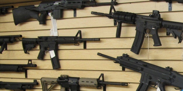 Frank Loane, owner of Pasadena Pawn and Gun, stands in front of a wall of assault rifles at his store in Pasadena, Md., on Th
