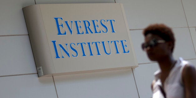 This photo taken July 8, 2014 shows a person walking past an Everest Institute sign in a office building in Silver Spring, Md. The Education Department says a former federal prosecutor will monitor a troubled for-profit education company that has agreed to sell or close its campuses. Corinthian Colleges has agreed to close a dozen U.S. campuses in 11 states and place 85 up for sale. The company serves 72,000 students and owns Everest College, Heald College and WyoTech schools. The department has said the company failed to provide adequate paperwork and comply with requests to address concerns about its practices. (AP Photo/Jose Luis Magana)