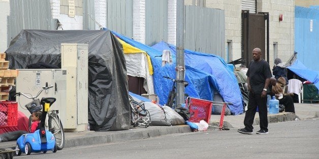 A man walks beside a row of tents for the homeless in Los Angeles, Califorinia on May 12, 2015. AFP PHOTO / FREDERIC J. BROWN (Photo credit should read FREDERIC J. BROWN/AFP/Getty Images)