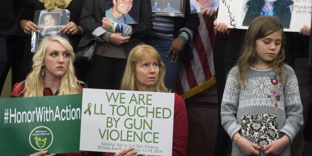 Relatives of victims of gun violence and gun violence prevention advocates hold up photos of victims during a press conferenc
