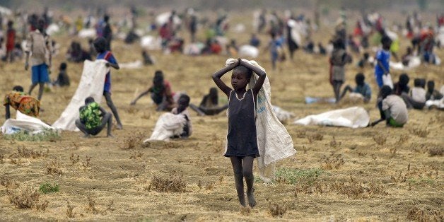 TO GO WITH AFP STORY BY AYMERIC VINCENOT Children flock with containers to a field demarcated for food-drops at a village in Nyal, an administrative hub of Panyijar county in Unity state, south Sudan, on February 24, 2015. Isolated by the Sudd,the world's largest marsh area, population Nyal is protected from the horrors of war that ravaged South Sudan but starved and exposed to disease. Almost all Panyijar County, about 60,000 people dependent on food aid parachuted by the World Food Programme (WFP) says local prefect Tap Puot John, a member of the 'opposition' whose troops fighting the government army since December 2013 control the area.. AFP PHOTO/TONY KARUMBA (Photo credit should read TONY KARUMBA/AFP/Getty Images)