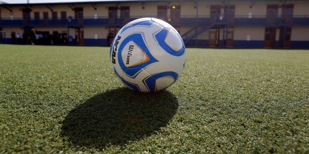 A soccer ball rests on an artificial turf soccer field in a courtyard at the Karnes County Residential Center, Thursday, July 31, 2014, in Karnes City, Texas. Federal officials gave a tour of the immigration detention facility that has been retooled to house adults with children who have been apprehended at the border. (AP Photo/Eric Gay)