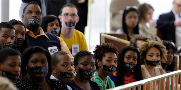 Members of North Carolina student chapters of the NAACP and opponents of voter ID legislation wear tape over their mouths while sitting silently in the gallery of the House chamber of the North Carolina General Assembly where lawmakers debated and voted on voter identification legislation in Raleigh, N.C., Wednesday, April 24, 2013. (AP Photo/Gerry Broome)