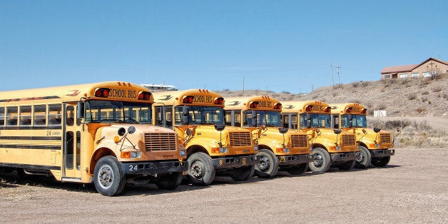 The quintessential yellow schoolbuses of America, lined up back at their desert depot.