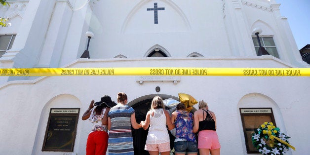 A group of women pray together at a make-shift memorial on the sidewalk in front of the Emanuel AME Church, Thursday, June 18