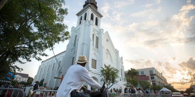 A bicyclist rides in front of the Emanuel AME Church, Sunday, June 21, 2015, before the first worship service since nine people were fatally shot at the church during a Bible study group, in Charleston, S.C. (AP Photo/Stephen B. Morton)
