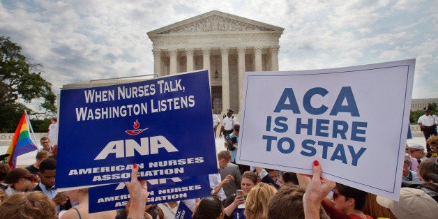 Supporters of the Affordable Care Act hold up signs as the opinion for health care is reported outside of the Supreme Court i