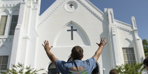 People listen to the Sunday service outside the Emanuel AME Church June 21, 2015 in Charleston, South Carolina. Large crowds are expected at Sunday's service at the black church in Charleston where nine African Americans were gunned down, as a chilling website apparently created by the suspected white supremacist shooter emerged. The service will be the first since the bloodbath on Wednesday at the Emanuel African Methodist Episcopal Church in the southern state of South Carolina, which has fuelled simmering racial tensions in the United States and reignited impassioned calls for stronger gun-control laws. AFP PHOTO/BRENDAN SMIALOWSKI (Photo credit should read BRENDAN SMIALOWSKI/AFP/Getty Images)