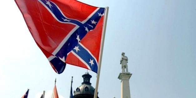 COLUMBIA, SC - JULY 1: The Confederate flag is waved by supporters in protest of its removal from the Capitol, 01 July 2000 in Columbia, SC. The Confederate flag was removed from atop the Statehouse dome and a Confederate battle flag was raised on a 30-foot pole at the Confederate Soldier Monument directly in front of the Capitol. (Photo credit should read ERIK PEREL/AFP/Getty Images)