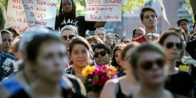 Muhiyidin D'baha holds two signs during a remembrance march in memory of the Emanuel AME Church shooting victims Saturday, June 20, 2015, in Charleston, S.C. (AP Photo/Stephen B. Morton)